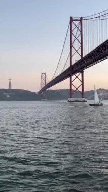 25 Nisan 'da Lizbon' daki Tagus Nehri üzerinde gün batımında bir yelkenli köprünün altından geçecek. Portekiz tarihi.
