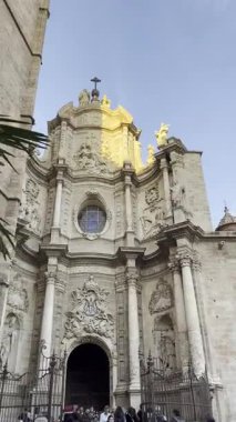 Yeşil palmiye ağaçlarından Valencia 'nın eski kasabasının merkezindeki tarihi bir binaya bakın: Güneşli bir yaz gününde gün batımı Katedral' i aydınlatır. İspanya 'nın simgesi.