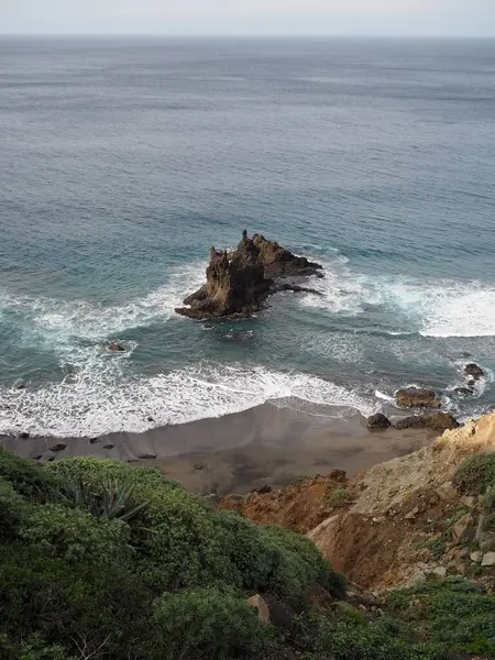 Benijo sahilinde mavi suyu ve Atlantik okyanusu dalgaları olan alışılmadık şekilli siyah bir kaya. Tenerife 'nin volkanik manzarası, Kanarya Adaları, İspanya.