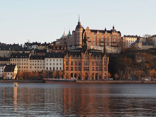 İsveç 'in Stockholm kentinden, Sodermalm bölgesinin tarihi manzarası, gün batımının altın saatinde. Mariaberget Riddarfjarden suyuna yansıyor. İskandinav mimarisi.