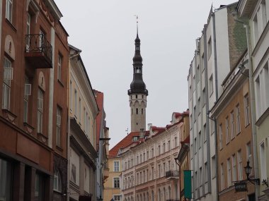Tallinn, Estonya 'daki eski şehrin Avrupa sokakları. Bulutlu bir günde Tallinn Belediye Katedrali 'nin kulesinin manzarası