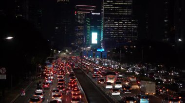 Trafiğin yoğun olduğu saatte. Şehir gece trafiği sıkışık. Şehir sokağı. Yoğun yol. Arabalar gece yolunu kullanıyor. Arabaların farları ve stop lambaları parlıyor. Araba trafiği gecesi. Hava kirliliği. 26 Şubat 2025. Jakarta, Endonezya