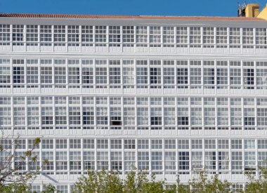 LA CORUNA, İspanya - 22 Nisan 2024: La Coruna, İspanya 'daki Kristal Şehir' de cam balkon ya da galeriler içeren beyaz bina cephesi.