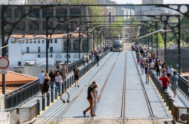 PORTO, PORTUGAL - 24 Nisan 2024: Portekiz 'in Porto kentindeki Luis 1 köprüsünde metro treninin önünden geçen turistler