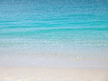 Plaj estetiği. Cennet adası. Kum kıyısı dalgalarla yıkanıyor. Kristal berrak turkuaz deniz suyu. Yaz tatili hayalleri kurar. 