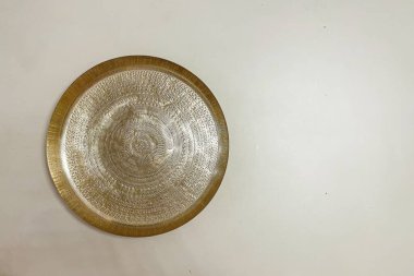 Yumuşak bej bir arka plana yerleştirilmiş karmaşık desenli büyük altın bir tepsi. Tepside metalik aksanlı zarif bir tasarım var. Lüks ve entelektüellik sergilemek için mükemmel..