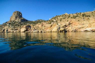 Deniz kıyısında kayalar ve dalgalar güneşli havada.