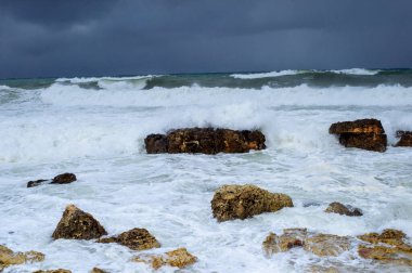 Fırtınada kayalık kıyıların arka planında fırtınalı deniz dalgaları.