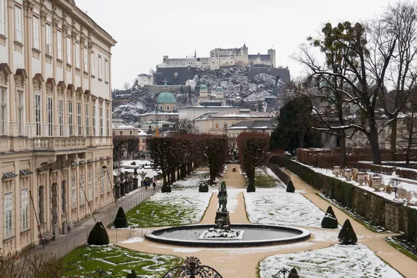 Salzburg 'da kış yürüyüşü, kaldırım taşı sokaklar, büyüleyici eski binalar ve kar ve histor örtüsüne sarılmış yüksek kale.