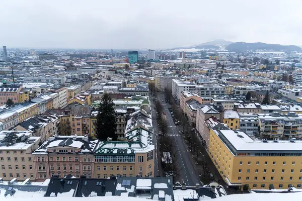 Salzburg 'da kış yürüyüşü, kaldırım taşı sokaklar, büyüleyici eski binalar ve kar ve tarihten oluşan bir battaniyeye sarılmış yüksek kale..