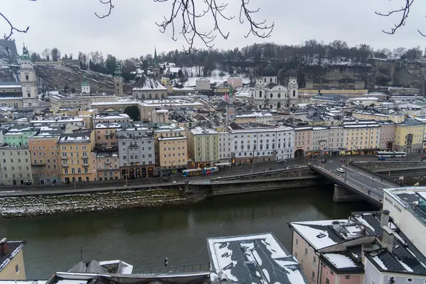 Salzburg 'da kış yürüyüşü, kaldırım taşı sokaklar, büyüleyici eski binalar ve kar ve tarihten oluşan bir battaniyeye sarılmış yüksek kale..