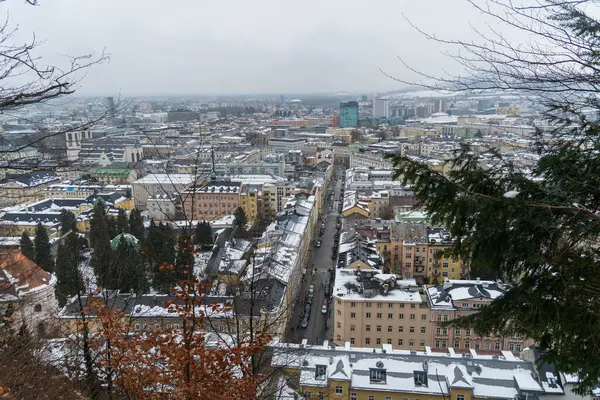 Salzburg 'da kış yürüyüşü, kaldırım taşı sokaklar, büyüleyici eski binalar ve kar ve tarihten oluşan bir battaniyeye sarılmış yüksek kale..