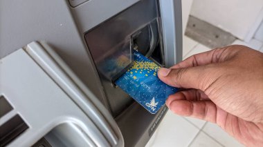 Otomatik Teller Machine (ATM) 'den para çekmek ya da para çekmek için elinde ATM kartı tutan bir erkek ya da kadının yakın çekimi. Finans ve iş konsepti