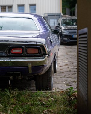 Lublin, Polonya - 26.09.2024. Mor Dodge Challenger 1972 (JH-23) modern arabalar arasındaki otoparkta.