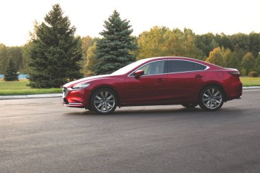 Brest, Belarus - 08 27 2019: Mazda 6 (GL) gün batımında boş yolda, arka planda ağaçlar.