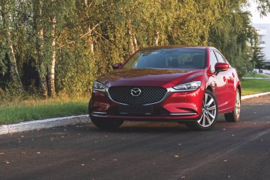 Brest, Belarus - 08 27 2019: Mazda 6 (GL) gün batımında boş yolda, arka planda ağaçlar.