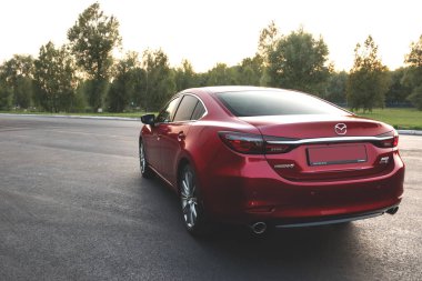 Brest, Belarus - 08 27 2019: Mazda 6 (GL) gün batımında boş yolda, arka planda ağaçlar.
