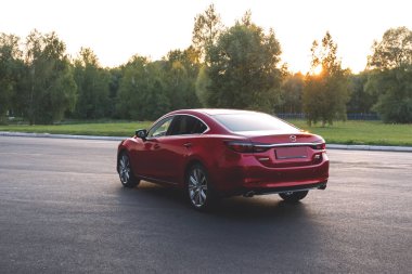 Brest, Belarus - 08 27 2019: Mazda 6 (GL) gün batımında boş yolda, arka planda ağaçlar.