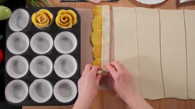 Kızın elleri, muffin pişirmek için kalıplı ahşap bir masanın üzerinde patatesli puf böreği çeviriyor. Üst görünüm, yakın çekim