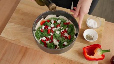 Bir kadın sağlıklı bir vejetaryen kahvaltısı hazırlıyor fırında ekmek ve sebzeler, ahşap masa, arka planda sebzeler. Fırın kabına tortilla, ıspanak, lahana, domates, paprika ve peynirli zeytin yağı ekle. Yakın çekim, üst görünüm