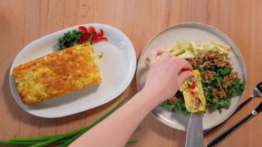Sebzeli, patatesli, karnabahar, lahana, domates, paprika, yumurta, peynir ve salatalı bir tabakta bir dilim hazır güveç alın. Bıçak ve çatal kullanarak, bir parça kes. Sağlıklı yemek. Yakın çekim, üst görünüm
