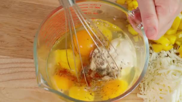 シェフの手はガラスの測定ボウルにスパイスで卵を混ぜ 野菜の背景に健康的な朝食のフリタタ 木製のテーブルを用意しています クローズアップ トップビュー — ストック動画