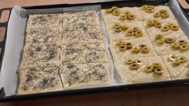 Fırında pişirilmeye hazır peynirli, jambonlu, susamlı ve zeytinli börek. Üçgen kekler, atıştırmalıklar. Yakın çekim, ön görüntü, kamera sorunsuz hareket ediyor..