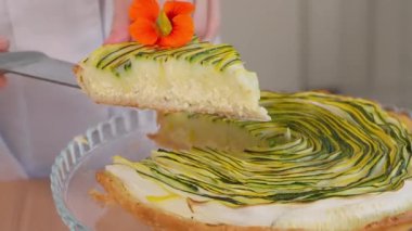 Şef bir spatula üzerinde çok renkli kabak ve peynir dolgulu bir parça turta gösteriyor. Yakın çekim, ön görüş, makro