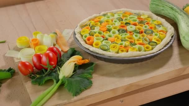 在烤盘中 在木制桌子上的蔬菜背景上 用五颜六色的西葫芦和胡萝卜做的馅饼 摄像机从左移到右移 — 图库视频影像