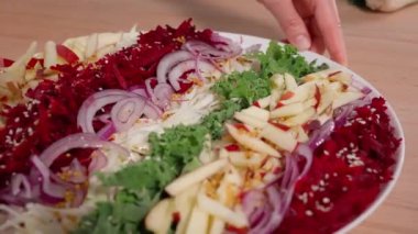 Şef pancar, elma, lahana ve soğan salatası sunar. Diyet yemekler, vitamin zengini sebzeler, vejetaryen yiyecekler. Yakın çekim, ön görüş, makro