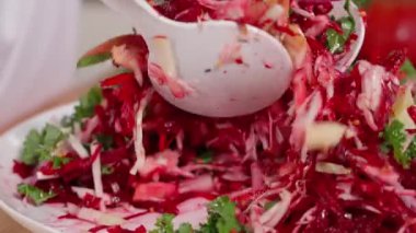Şef pancar, elma, lahana ve soğan salatası karıştırır. Fransız hardal sosu, limon suyu ve bal ile tatlandırılmış. Diyet yemekler, vitamin bakımından zengin sebzeler. Yakın çekim, ön görüş, makro