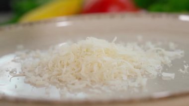 Parmesan peynirinin yakın plan çekimi ince rende bir tabağa koyuluyor. Macro, önden bak.