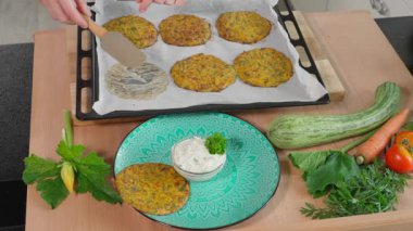 Şef, kabak kreplerini arkaplanda sebzelerle dolu ahşap bir masa olan soslu güzel bir tabağa aktarır. Vejetaryen yemeği, kabaklı gözleme, yakın çekim, üst manzara.