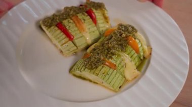Peynirle doldurulmuş kabak ve pesto soslu domates. Kabak aperatifi, kabak akordeonu, kabak tabağı, vejetaryen yemeği, hızlı atıştırma, parti. Yakın çekim, üst görünüm