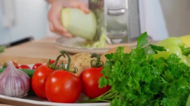 Şef, arka planda sebzeler olan, kabak rendesi rendeleyen, sağlıklı bir yemek hazırlıyor. Sağlıklı beslenme konsepti, vejetaryen yemekleri, vitamin zengini sebzeler, diyet. Yakın plan.