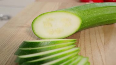 Tahta üzerinde dilimlenmiş yeşil kabak dilimleri. Sağlıklı beslenme konsepti, vejetaryen yiyecekler, vitamin, diyet ve sebze açısından zengin. Yakın çekim, ön görüş, makro