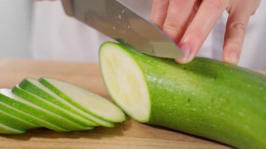 Şef yeşil kabağı bıçakla dilimleyip sağlıklı bir yemek hazırlıyor. Sağlıklı beslenme konsepti, vejetaryen yemekleri, sebzeler. Yakın çekim, ön görüş, makro