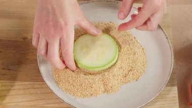 Ekmek kırıntıları ve baharatlarla kaplı beyaz kabak dilimleri ve üstüne domates sosu. Kabak yemeği, kabak tarifi, atıştırmalık bir şeyler. Yakın çekim, üst görüntü, hızlı hareket