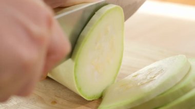 Bir kız tahta bir tahtada beyaz kabağı dilimlere ayırıyor. Sağlıklı beslenme konsepti, vejetaryen yiyecekler, vitamin, diyet ve sebze açısından zengin. Yakın plan, kenar görüş, makro