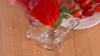 Üzerine kırmızı sos serpiştirilmiş çilekli bir parça jöleli süt tatlısı tabakta duruyor. Çilekli tatlıyı ısırmak için çatal kullan. Çilek soslu tatlı. Yakından, makro, önden.