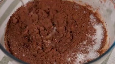 Şef sağlıklı bir çikolatalı tatlı hazırlıyor. Cam kasede, hamur ile kakao, şeker, muz ve yulaf ezmesini karıştırmak için kaşık kullanın. Yakın çekim, makro, üst görünüm