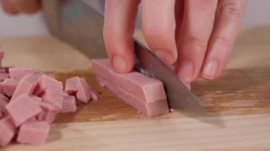 Şef ahşap bir tahtanın üzerinde keskin bir bıçakla jambonu küp küp keser. Kahvaltı için sosis, yumurta hazırlıkları. Jambonlu aperatif. Yakından, makro, önden.