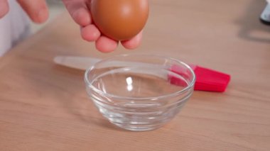 Şef bir yumurtayı cam bir kaba kırar, ahşap bir yüzeye vurur. Sağlıklı kahvaltı, öğle yemeği, akşam yemeği, sağlıklı beslenme konsepti hazırlıyor. Macro, önden bak.