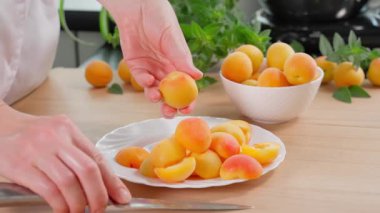 Kızın elleri kayısıları çukurlardan soymak için bıçak kullanıyor. Kayısı reçeli, kayısı reçelli tatlı, kayısı turtası, kayısı reçeli. Yakın plan, kenar görünüm