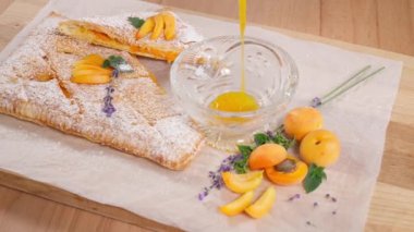 Reçelli, ahşap masa ve taze kayısılarla dolu bir turtanın arka planındaki cam kasede kayısı reçeli. Kayısı ve tatlı olsun. Yakın plan, ön görünüm