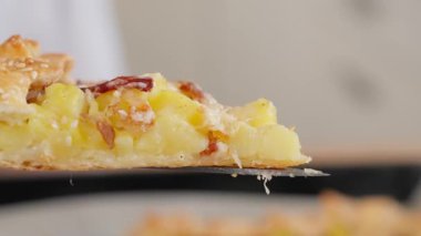 Makro dilimlenmiş taze fırında patates ve susam tohumlu pastırmalı turta. Patates tabakları, haşlanmış patatesler, turta doldurma ve atıştırmalıklar. Yakın plan, kenar görünüm