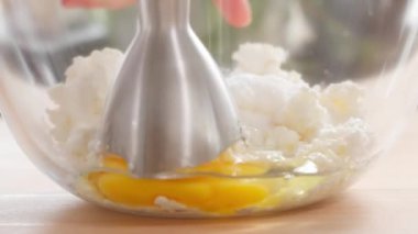 Makro. Krem peynir ve yumurtalar cam bir kaseye batırılmış blender ile doğranır. Panna cotta, krem peynir, hamur işi dolgu, süzme peynir zapikanka. Yakın plan, ön görünüm