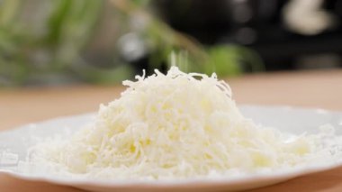 Makro. Peynir güzel bir rende rendelenir ve bir yığın içinde bir tabağa dönüştürülür. Parmesan, Gouda, sert peynir. Rendelenmiş peynir, fırında peynir, peynirli makarna. Yakın plan, ön görünüm