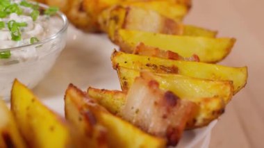 Pastırma, baharat ve krema soslu yuvarlak bir tabakta daireler çizerek dönüyor. Pastırmalı fırında patates, baharatlı patates. Yakın plan, ön görünüm