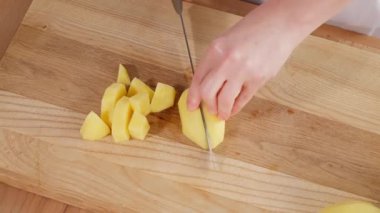 Çiğ patatesler keskin bir bıçakla, tahta bir tahtayla parçalara ayrılır. Patates tabağı, patates püresi, haşlanmış patates turta ve abur cubur. Yakın çekim, üst görünüm